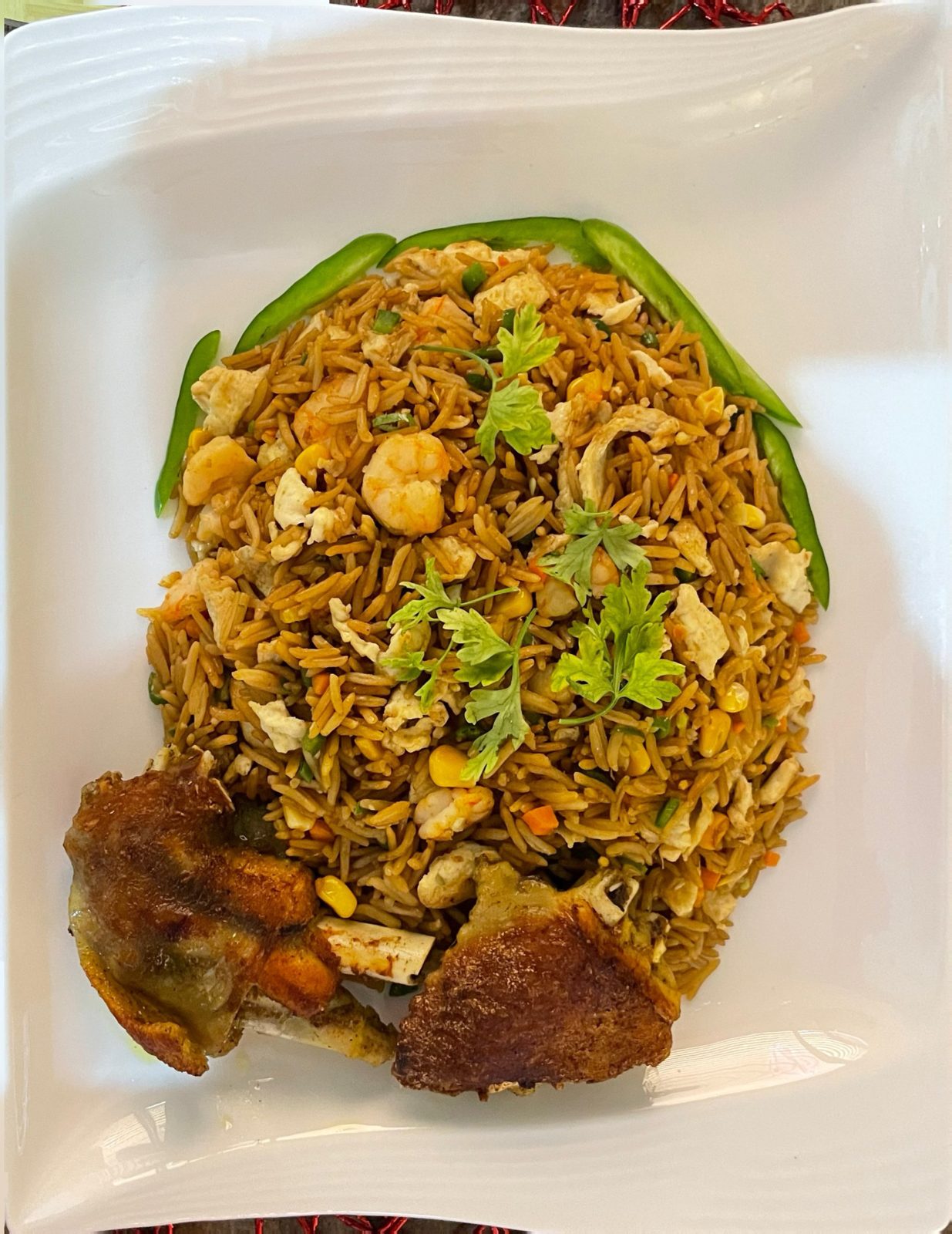 Special fried rice with prawns, chicken and fried plantain on a white plate